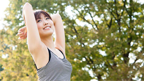 森の中で両腕をあげている健康的な女性